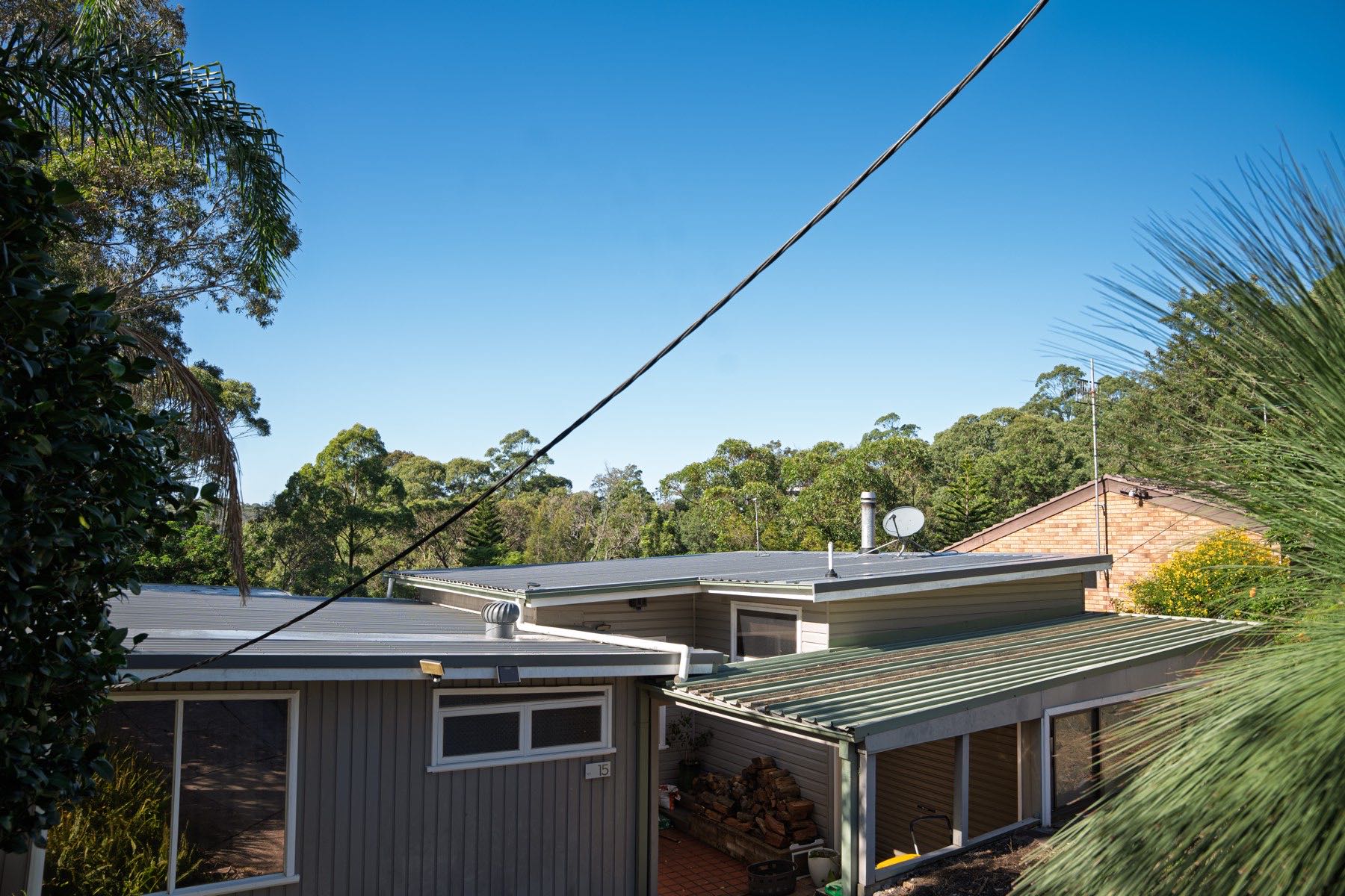 Completed metal re-roof among trees, seen from the road